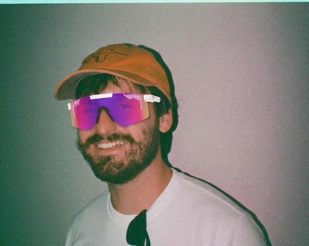Bearded guy in an orange cap wearing Radical Pink Pit Vipers (white frame, pink-to-purple lens)